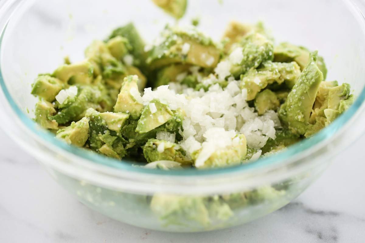 guacamole in a white bowl surrounded by chips