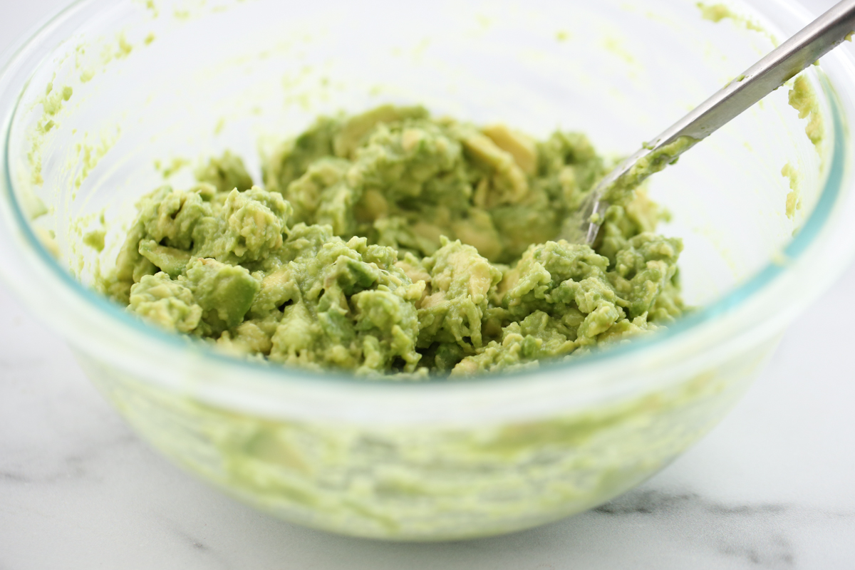 guacamole in a white bowl surrounded by chips