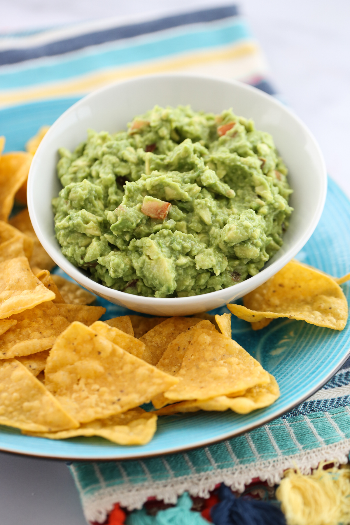 guacamole in a white bowl surrounded by chips