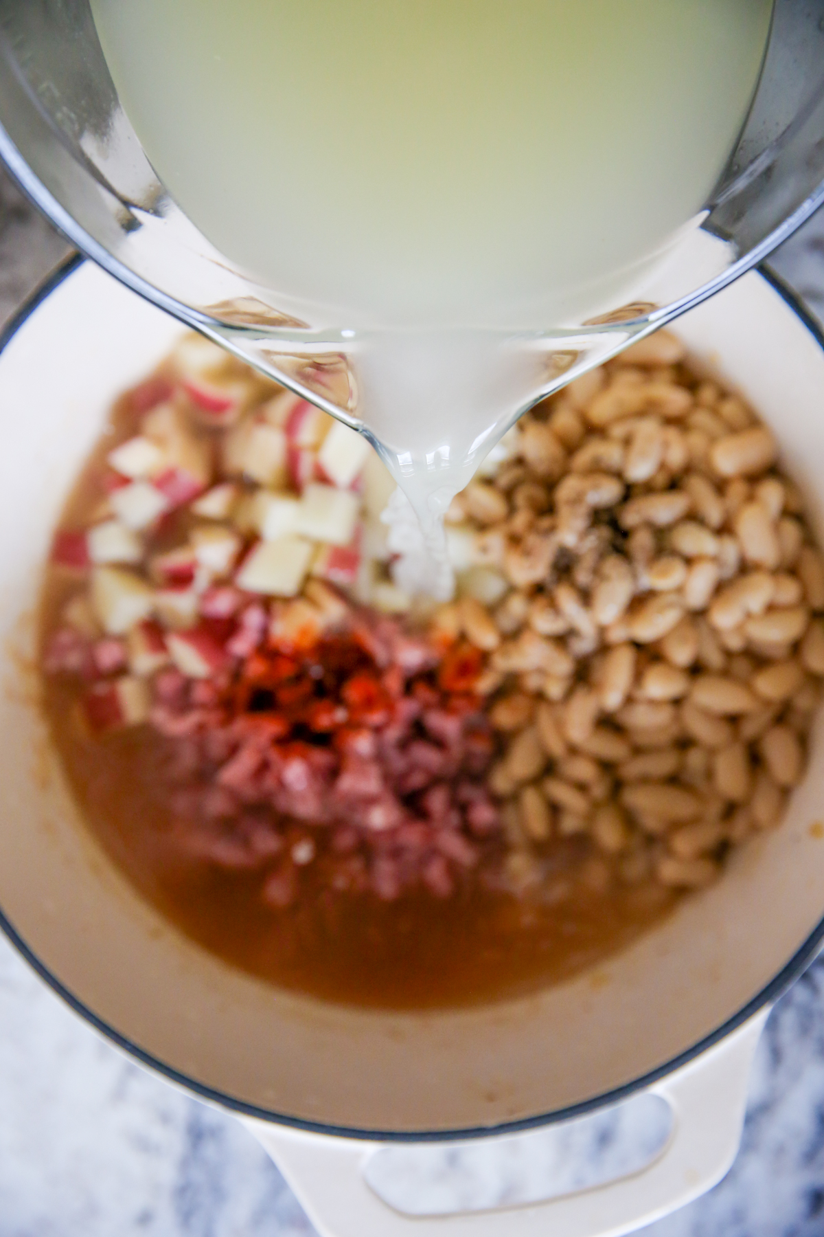 pouring chicken broth into a soup pot