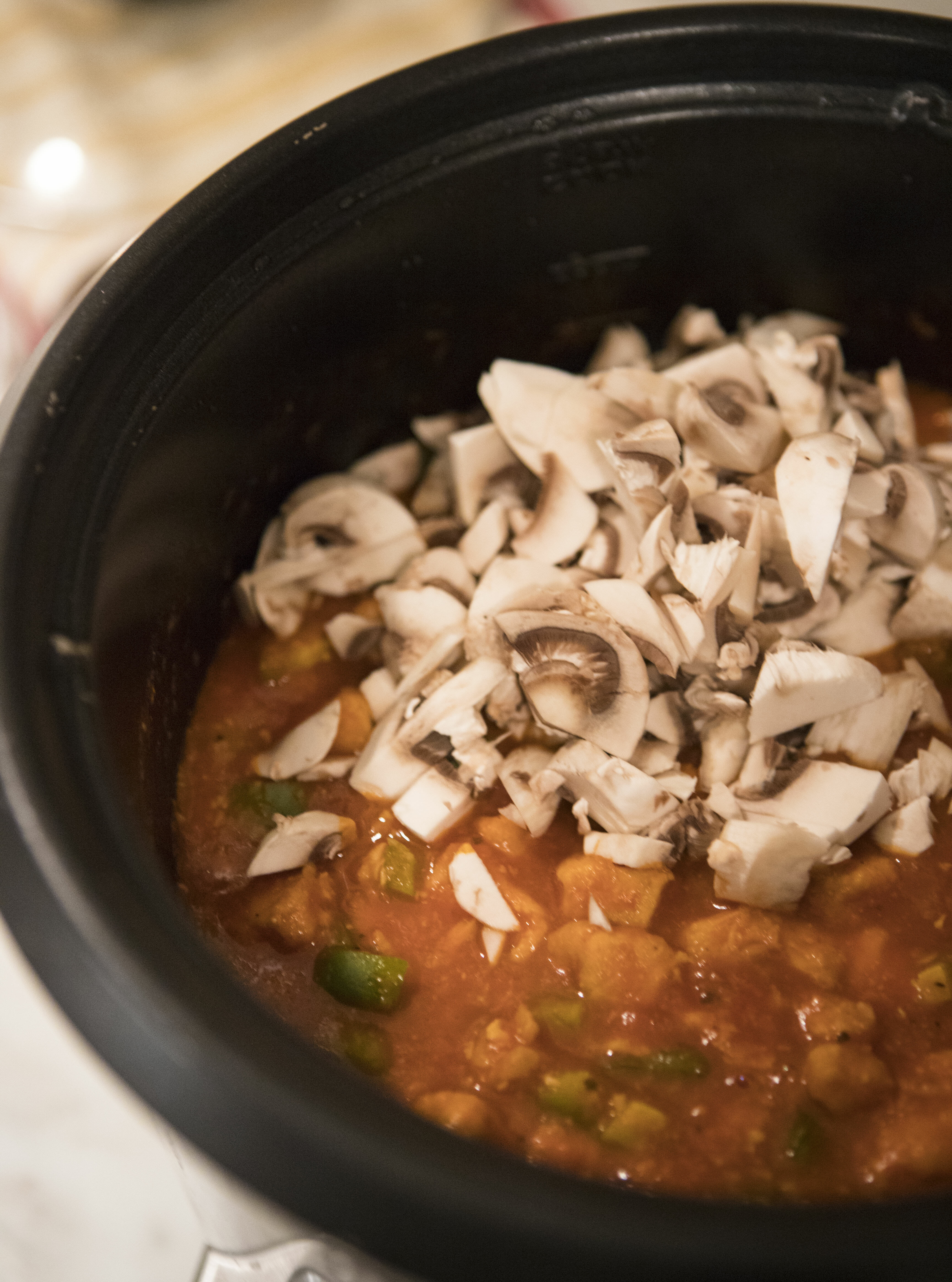 adding mushrooms and peppers to sauce