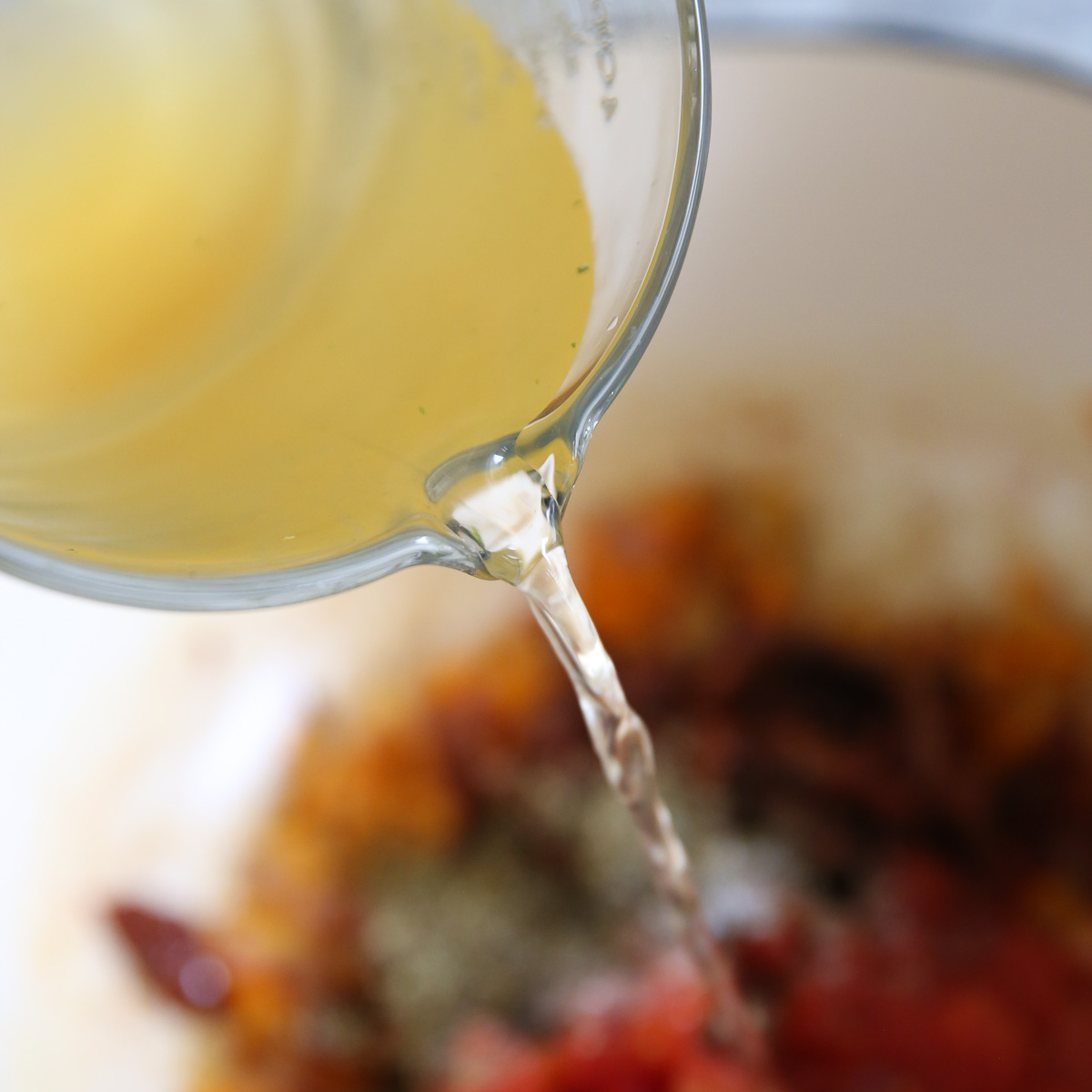 pouring broth into tomato soup