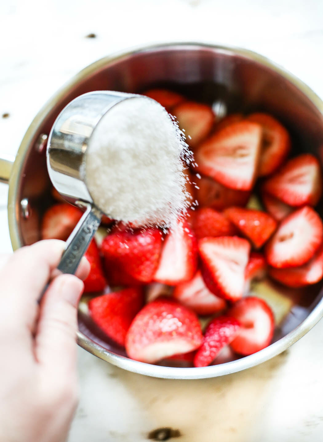 adding sugar to sliced strawberries