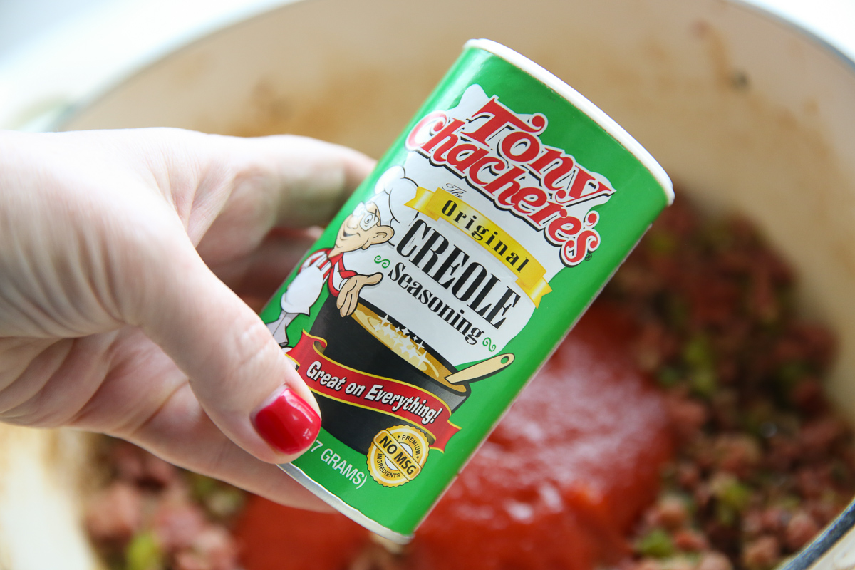 Holding a bottle of Tony's over a cooking pot of jambalaya