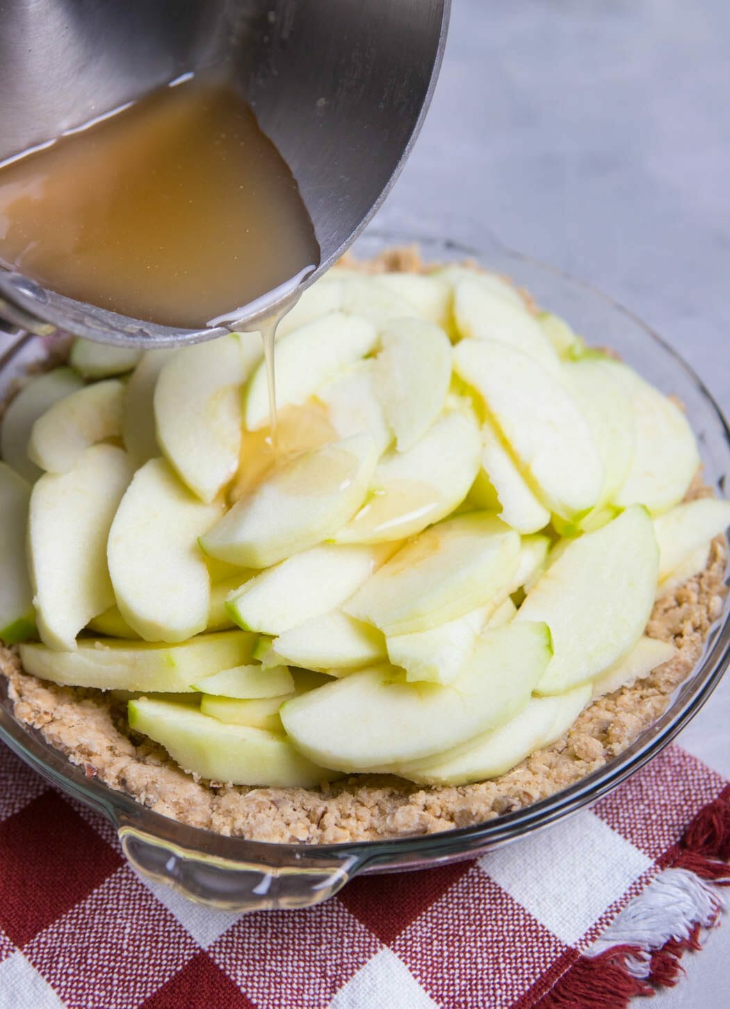 pouring syrup mixture over apples in Crumb Topped Apple Pie from Our Best Bites