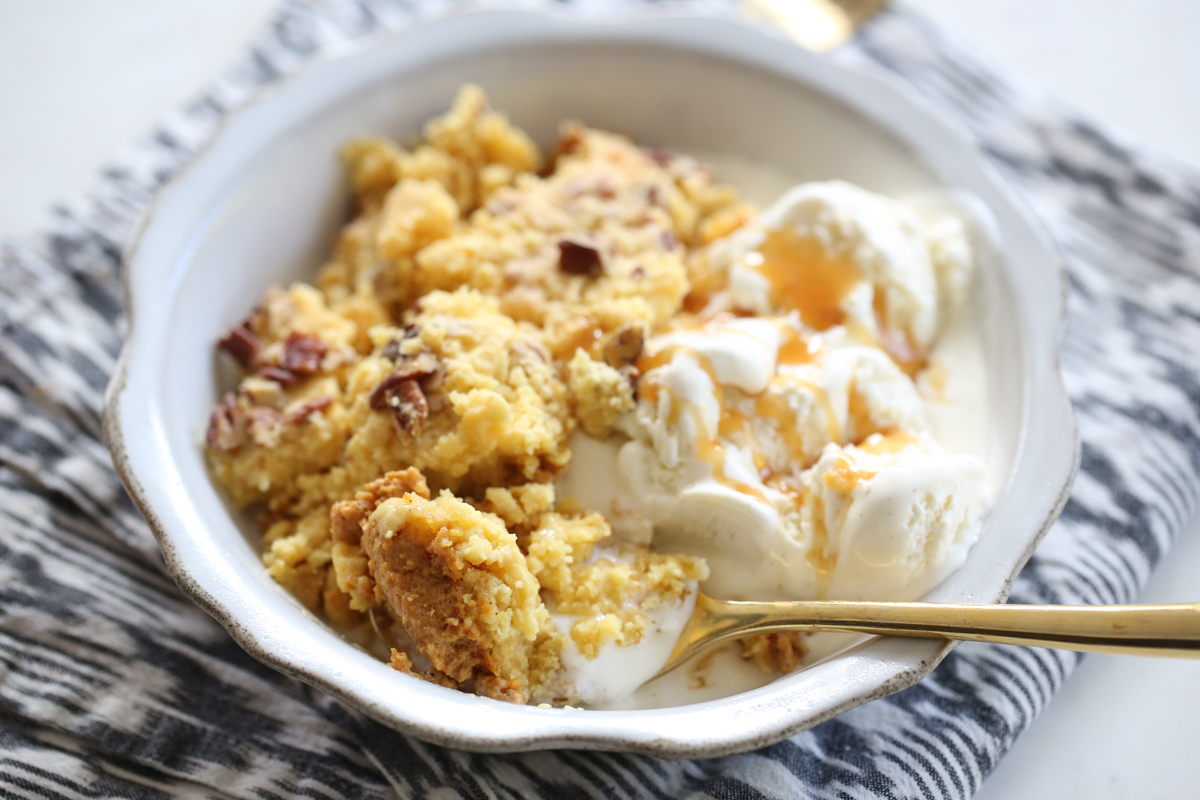 pumkin dump cake in a white bowl with ice cream