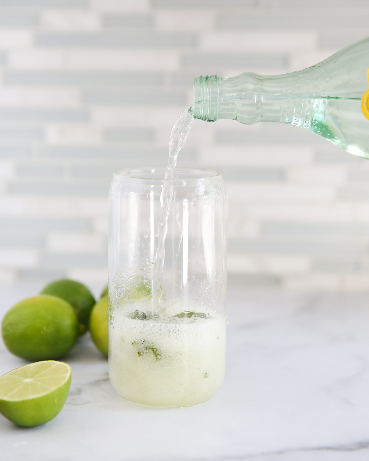 sparkling water pouring into mojitos