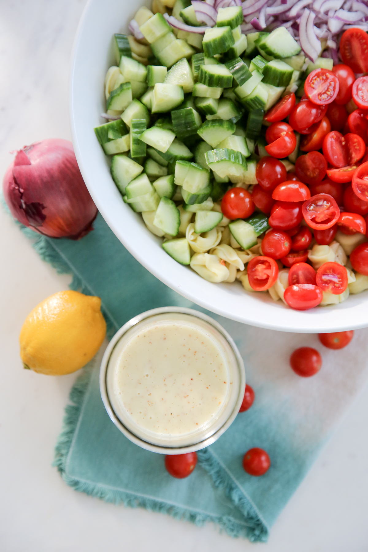 pouring dressing over pasta salad