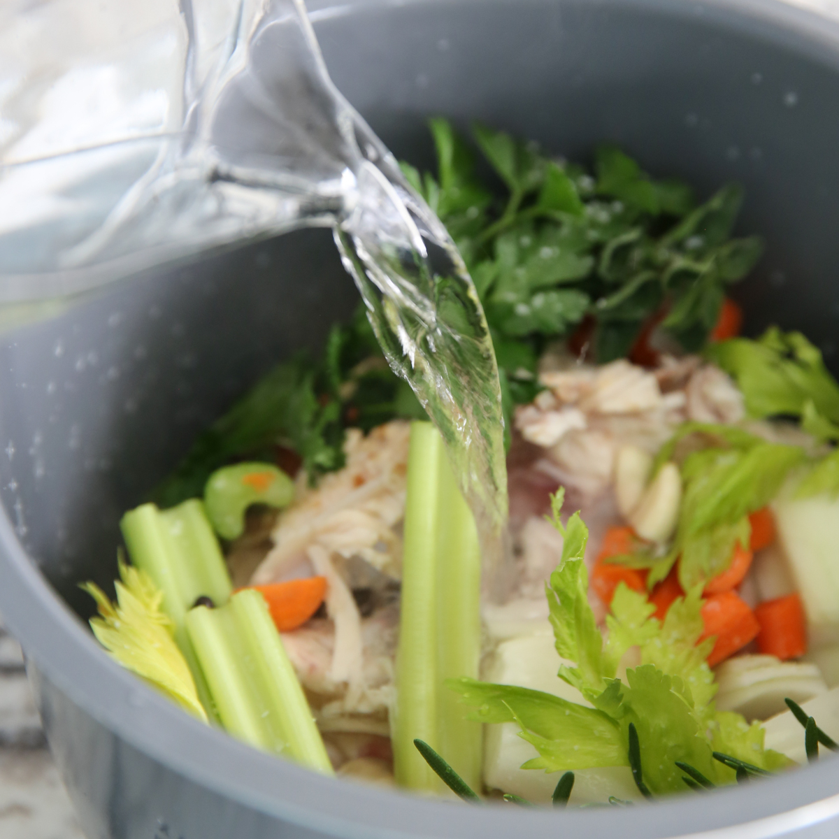 pouring water into Homemade Chicken Broth