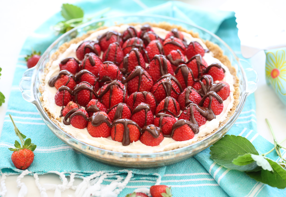 Cream pie with strawberries on top and chocolate drizzle
