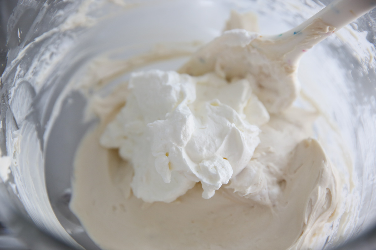 whipped cream getting folded in a mixing bowl