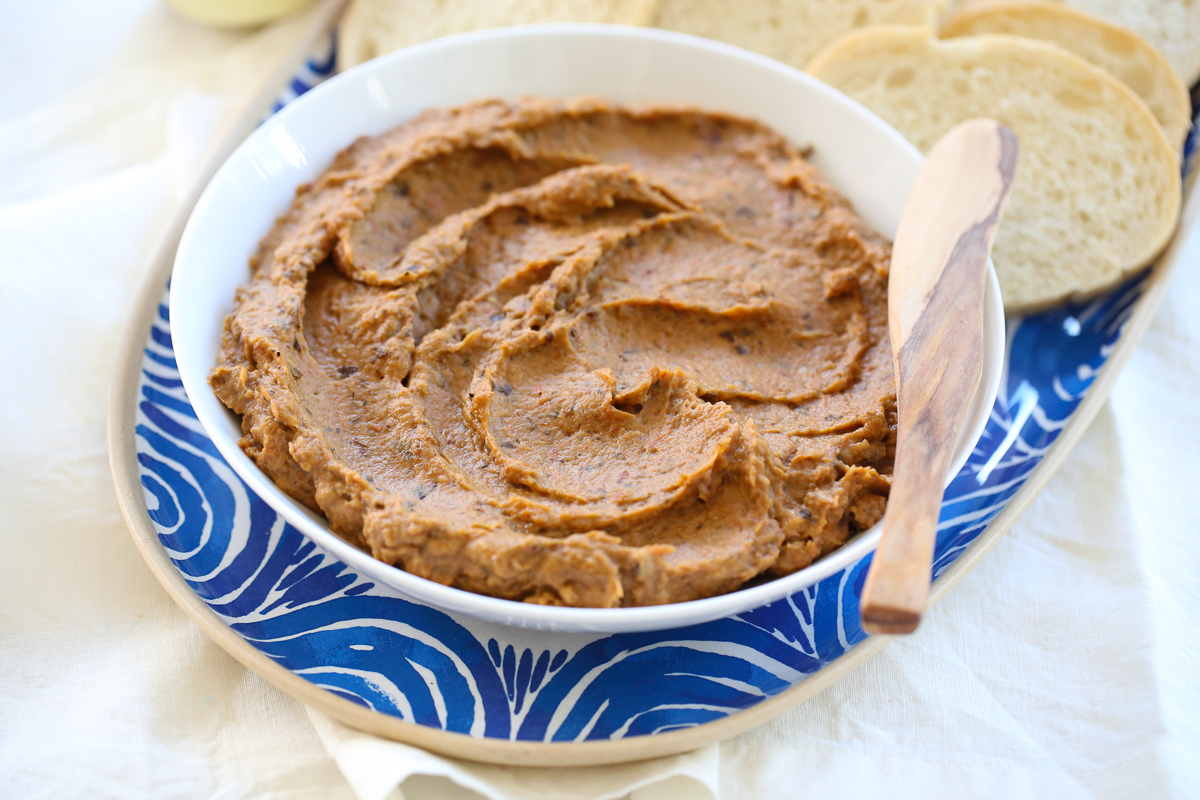 Eggplant spread in a white bowl with a spreader