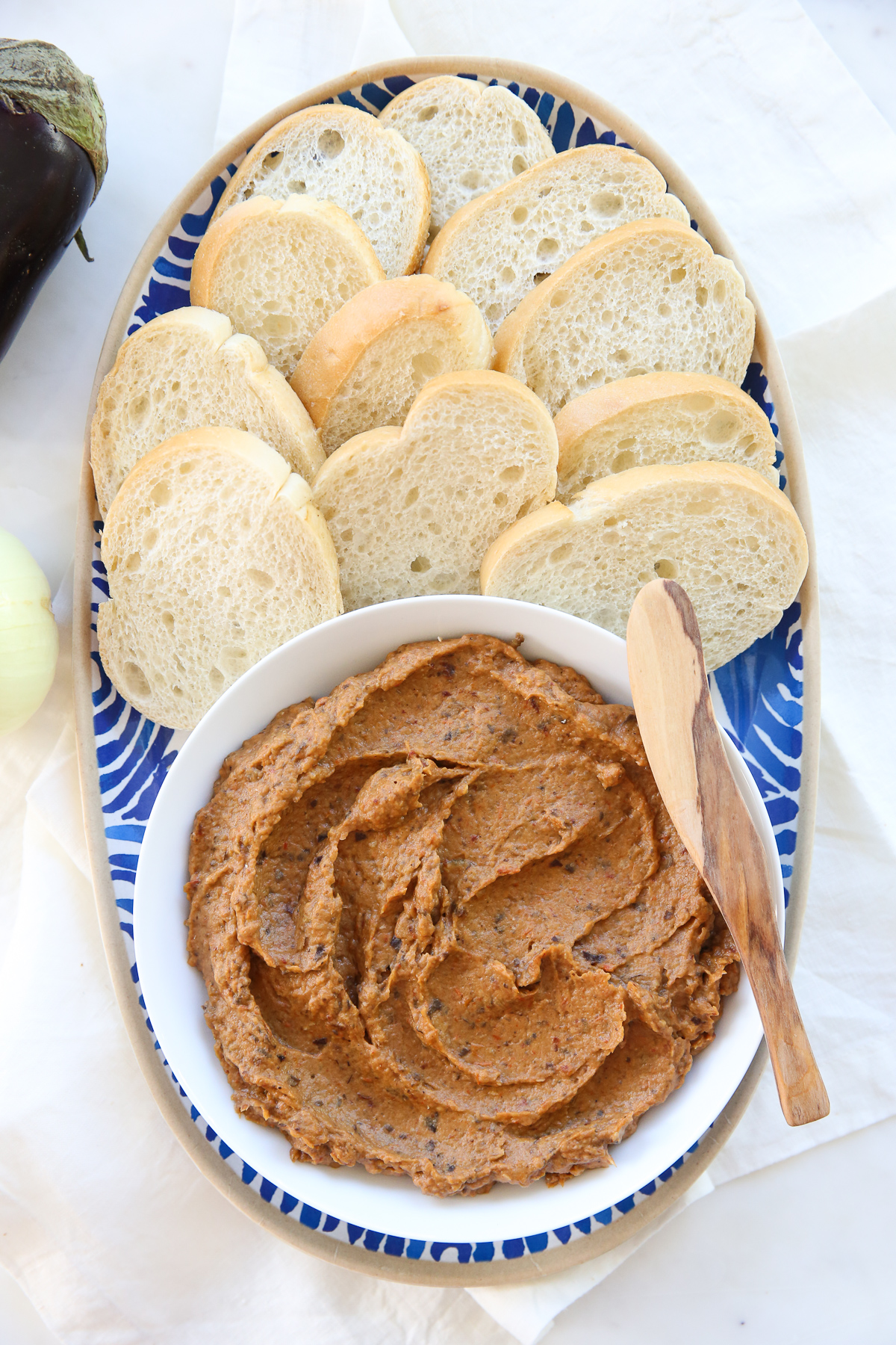 Eggplant spread in a white bowl with a spreader