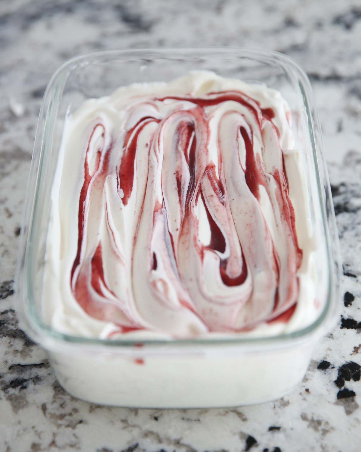 ice cream mixture in a glass container with berry swirl