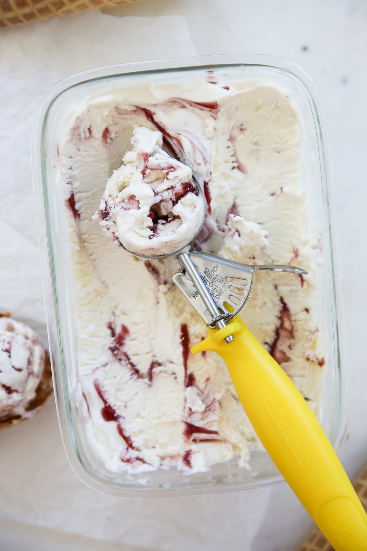 frozen ice cream mixture in a glass container with berry swirl