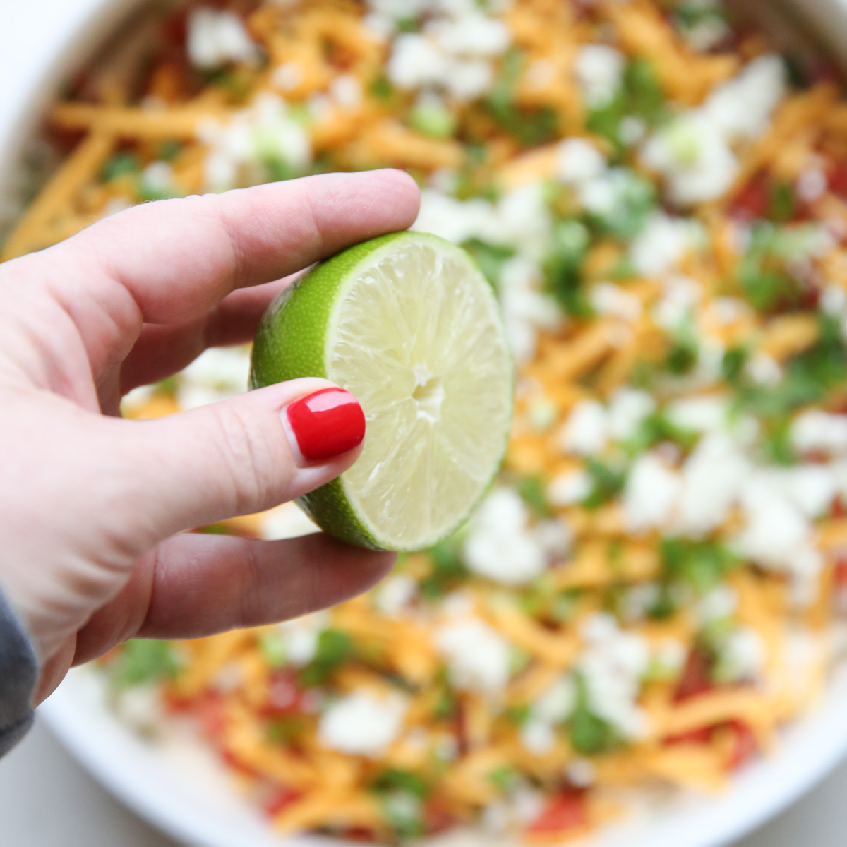 squeezing lime over 7 layer dip