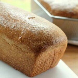 A loaf of freshly baked honey whole wheat bread on a cutting board.