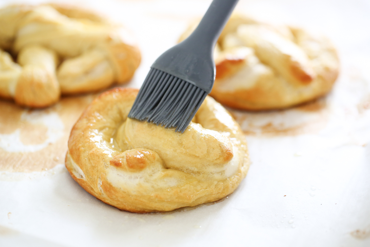 brushing butter on a baked soft pretzel