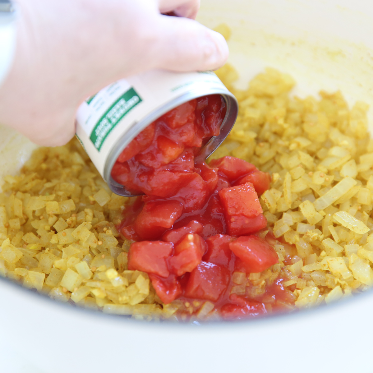 adding diced tomatoes to pot of veggies
