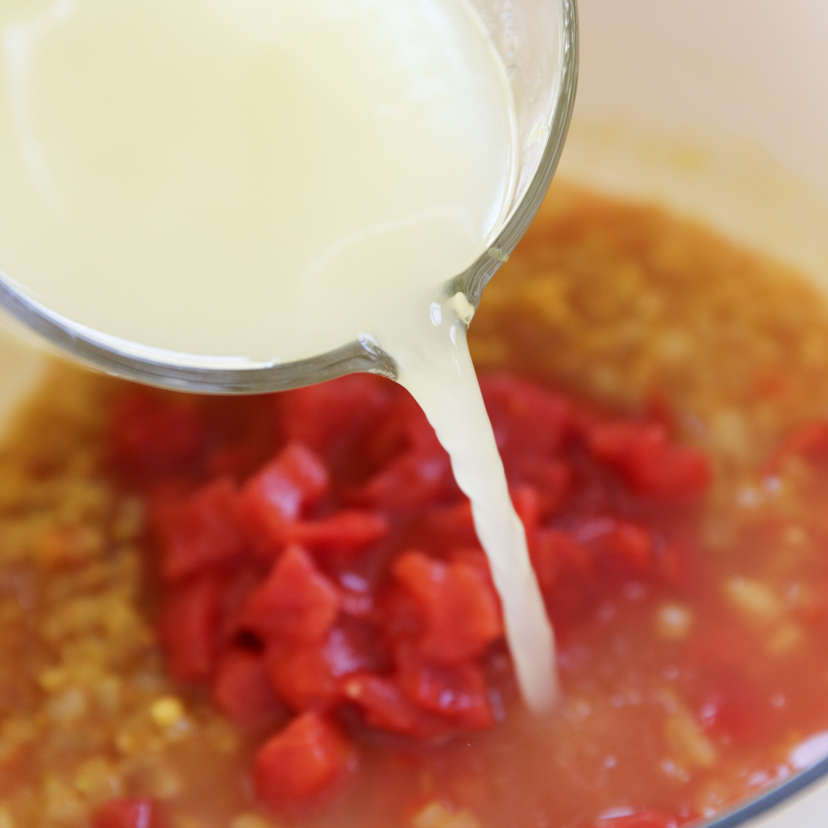 pouring chicken broth to red lentil pot