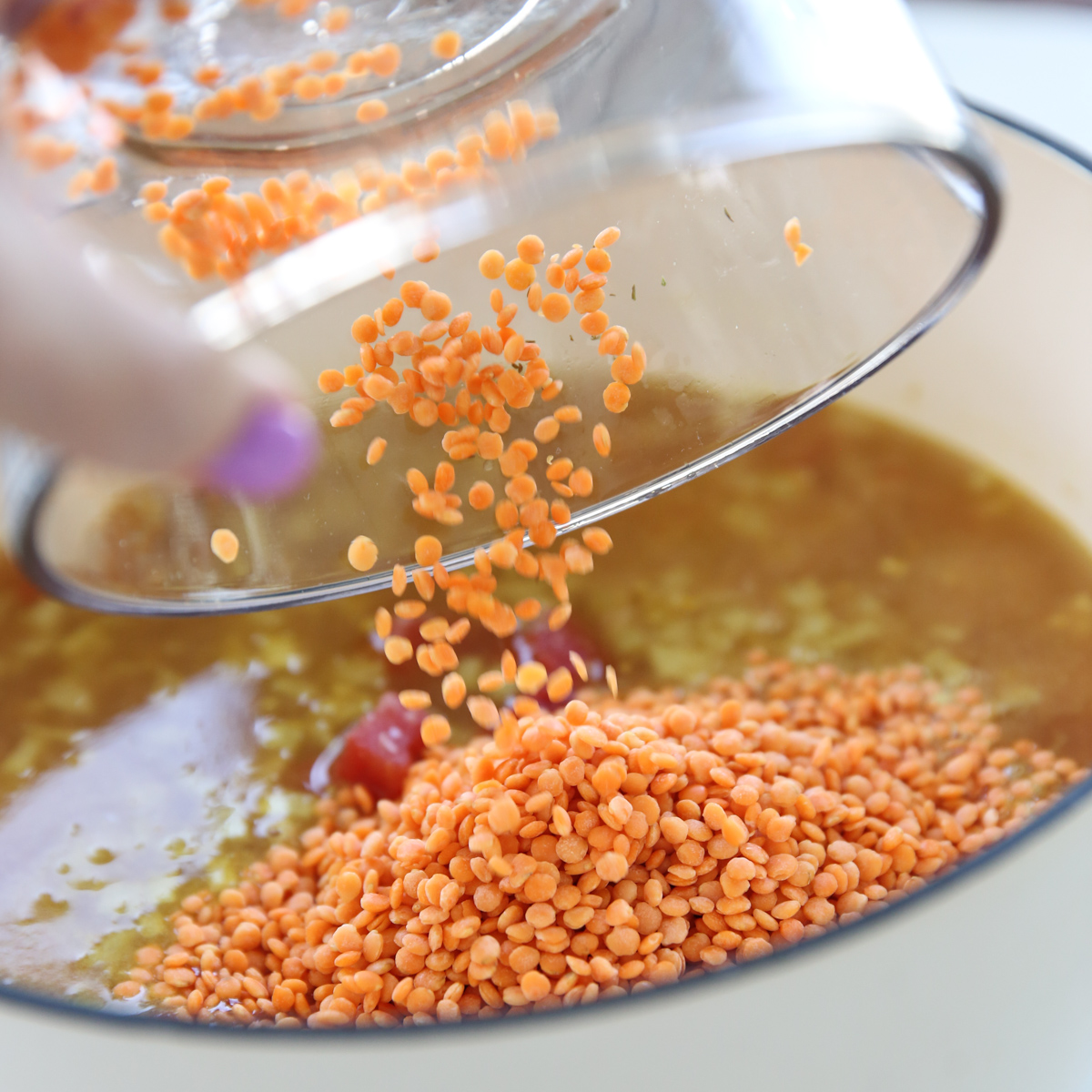 adding dry red lentils to a pot