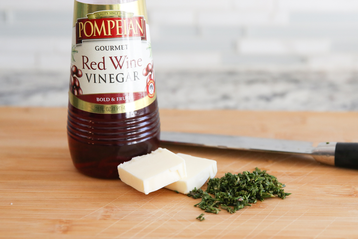 red wine vinegar with butter and rosemary on a cutting board