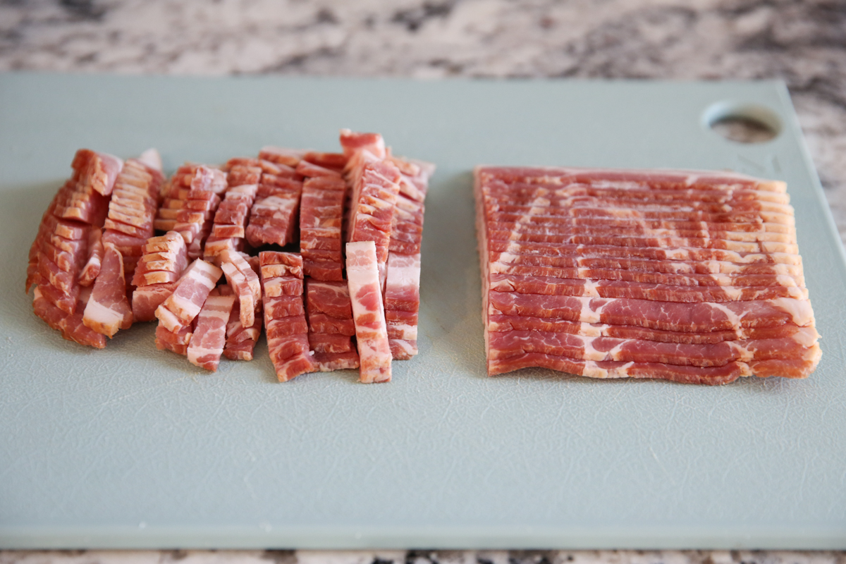 raw bacon being sliced on a cutting board