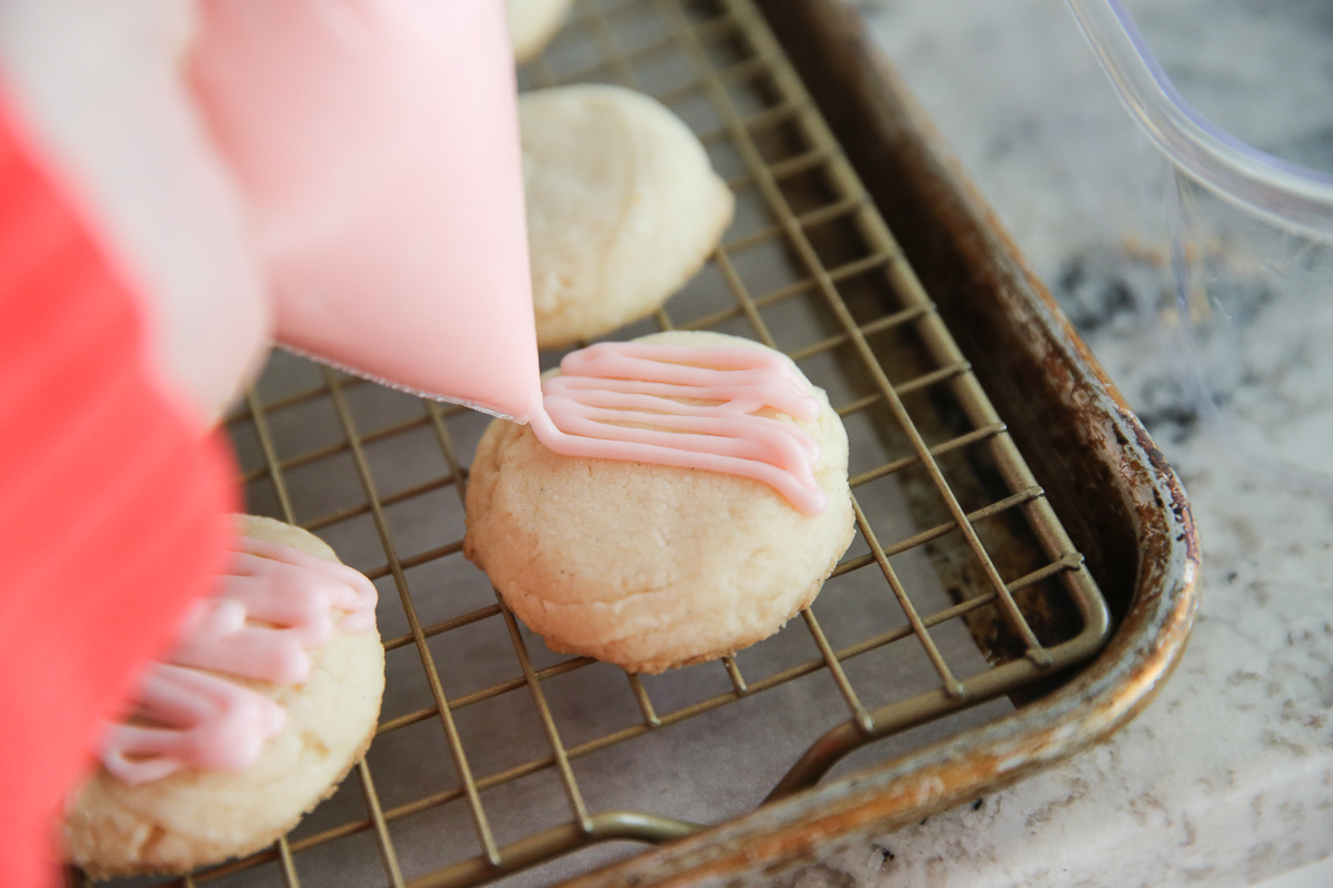 drizzling frosting on peppermint meltaway cookies