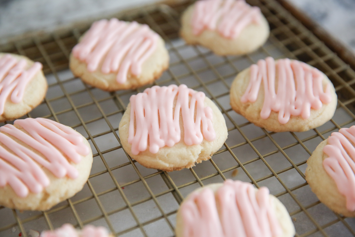 peppermint cookies with pink frosting on a cooling rack