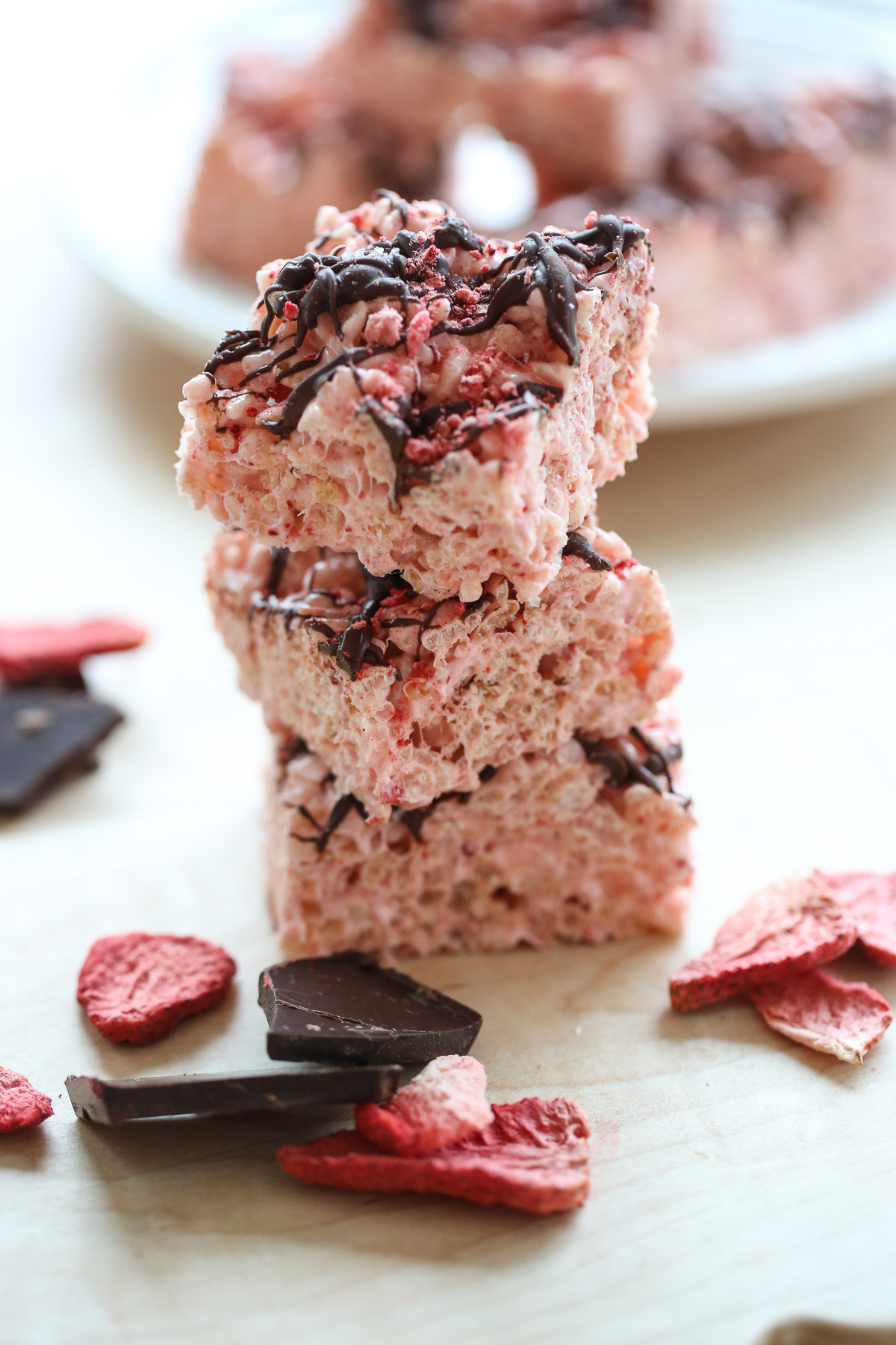 pink rice krispie treats in a pan drizzled with chocolate and berries