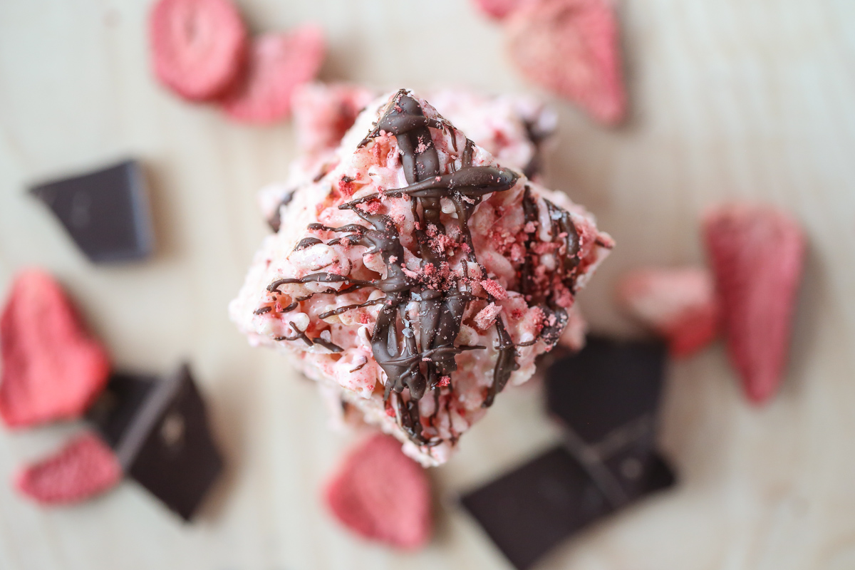 pink rice krispie treats in a pan drizzled with chocolate and berries