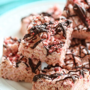 chocolate drizzled strawberry rice krispie treats on a plate