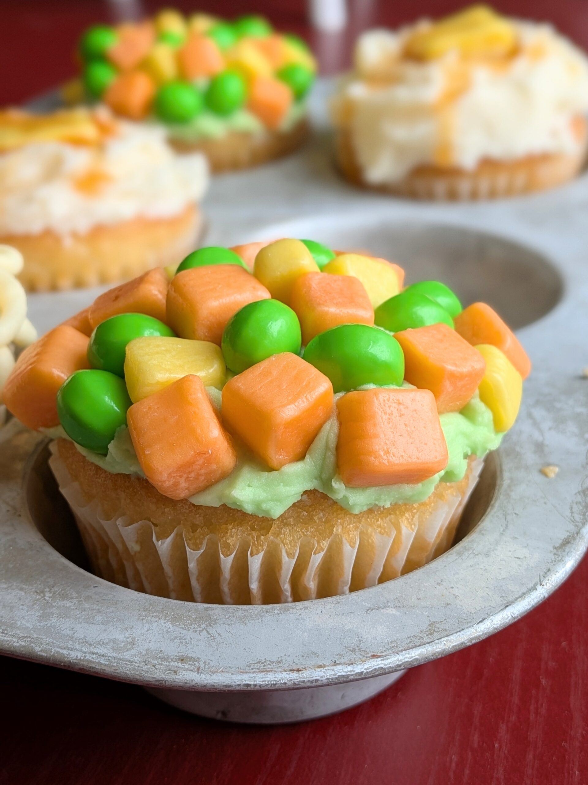 A silly cupcake decorated with candies to look like mixed vegetables.
