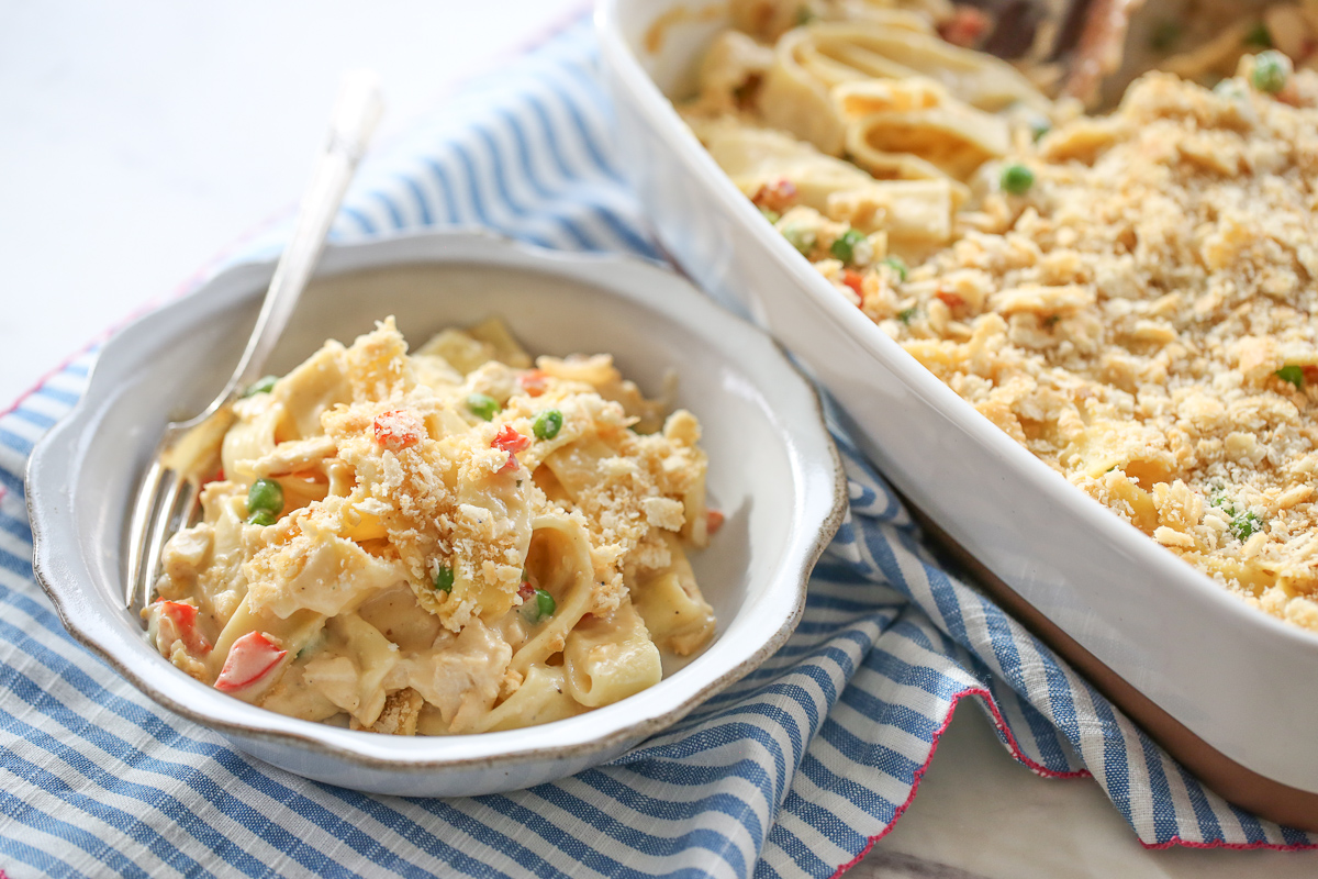 creamy chicken noodle casserole serving in a dish, next to a 9x13 pan