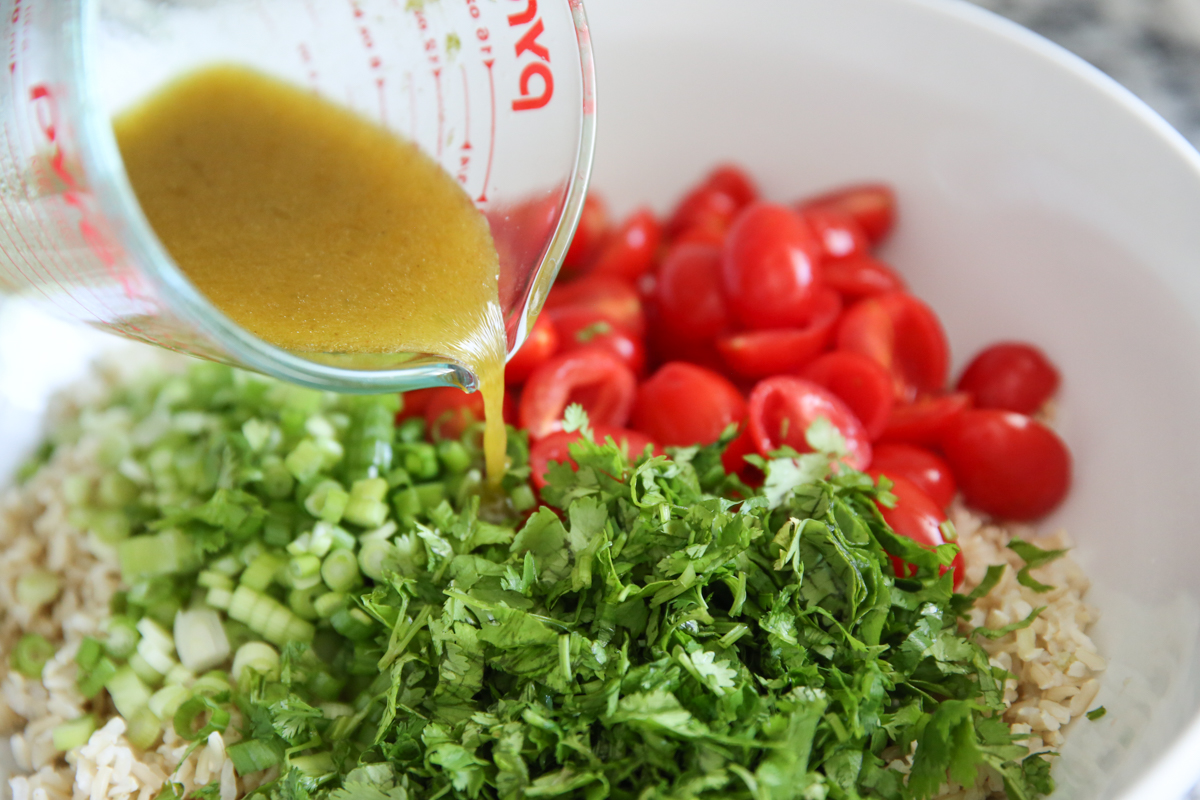 pouring dressing on a Southwest Brown Rice salad Recipe