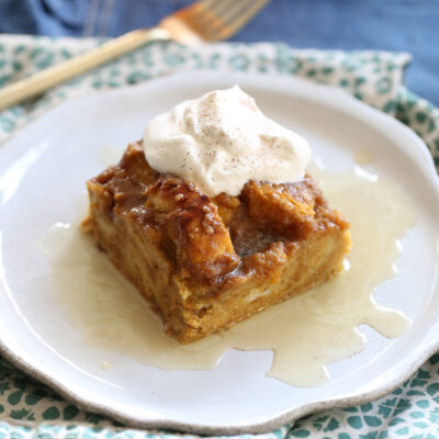 baked square of pumpkin french toast sliced on a plate with whipped cream on top