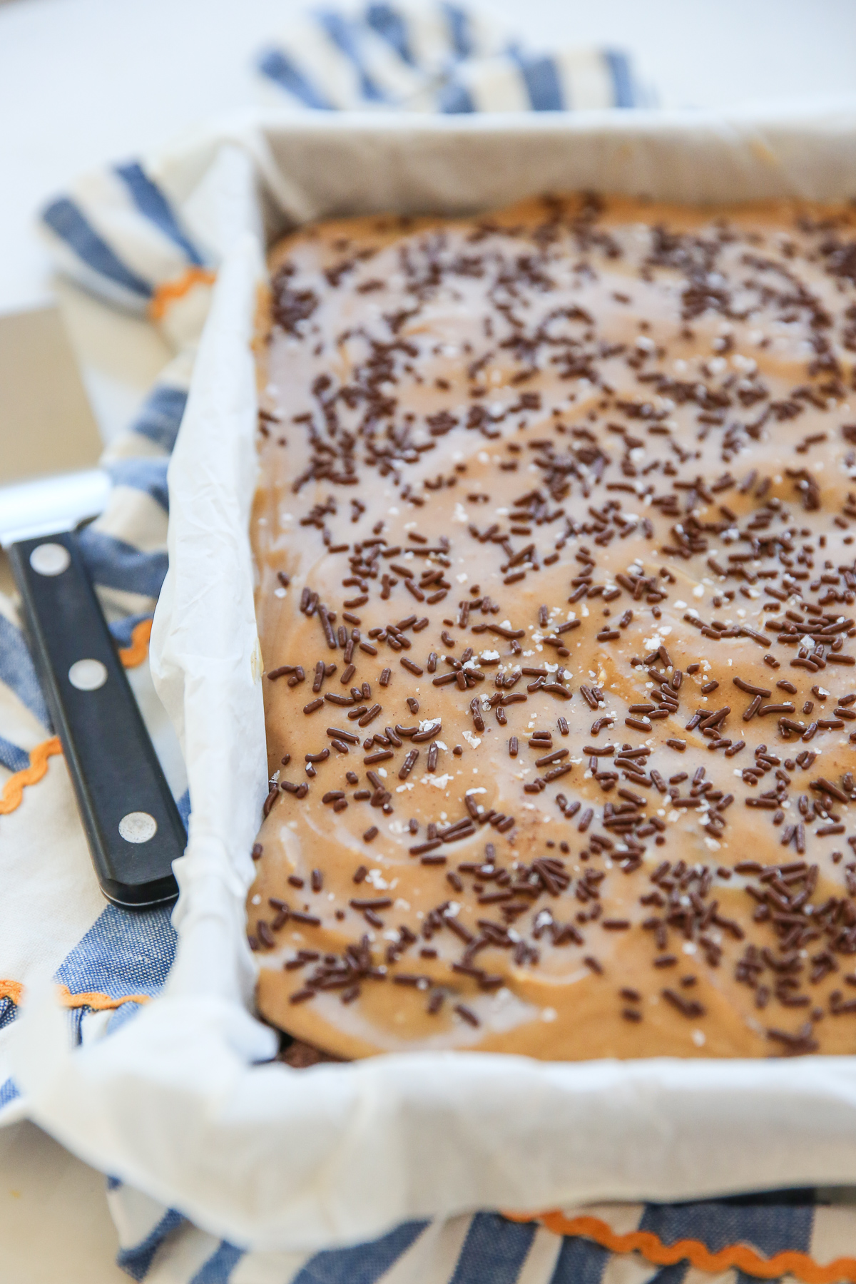 Chocolate Cake with peanut butter frosting in a cake pan with sprinkles and sea salt on top