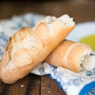 A crusty loaf of artisan bread, broken in half and laid on a cloth napkin.