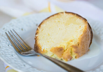 A slice of lemon lime soda Bundt cake rests on a white plate next to a fork. 
