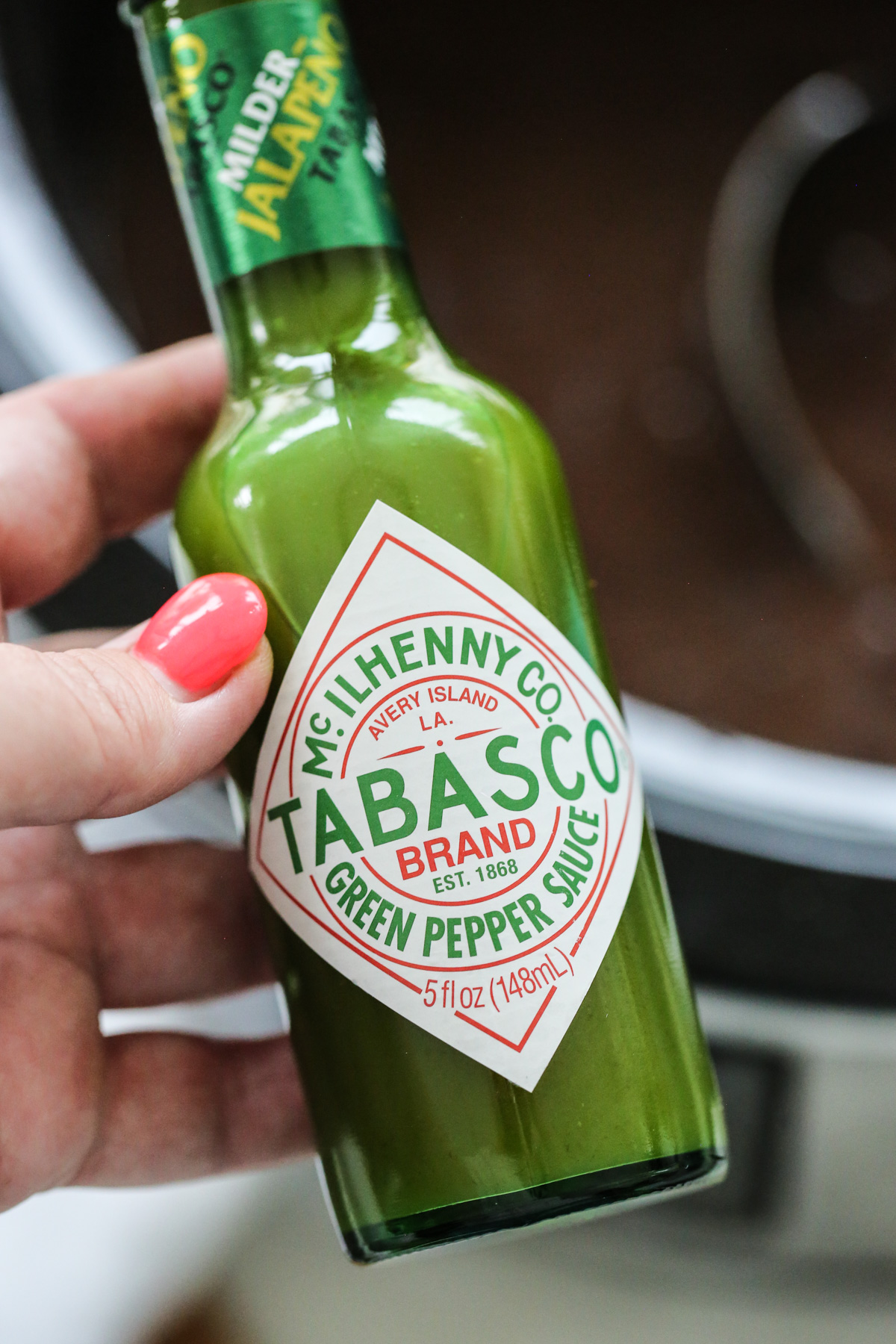 womans hand with a bottle of tobasco sauce