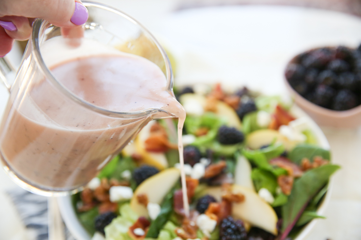 pouring salad dressing over salad