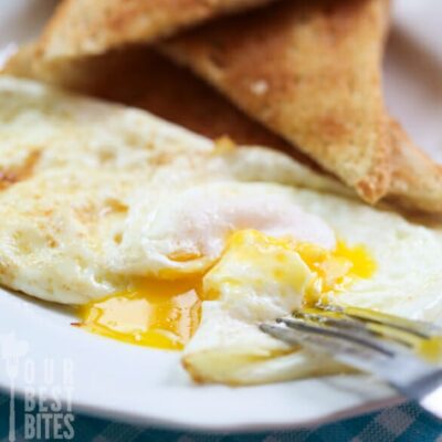 A perfect fried egg on a plate with toast.