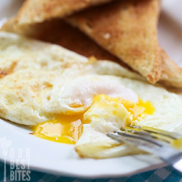 A perfect fried egg on a plate with toast. 