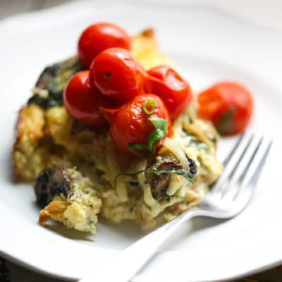 Caramelized Onion Strata on a plate with a fork and tomatoes