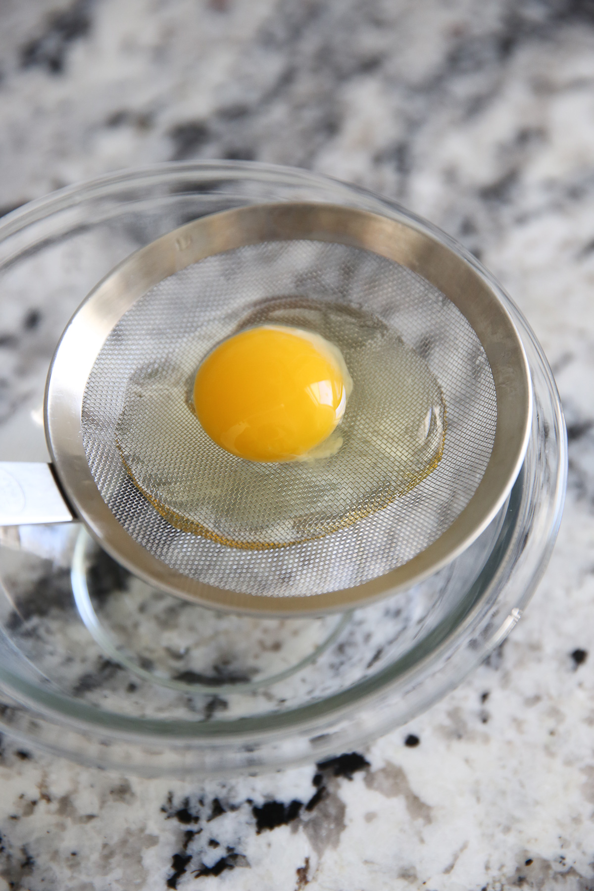 egg in a mesh strainer over a bowl