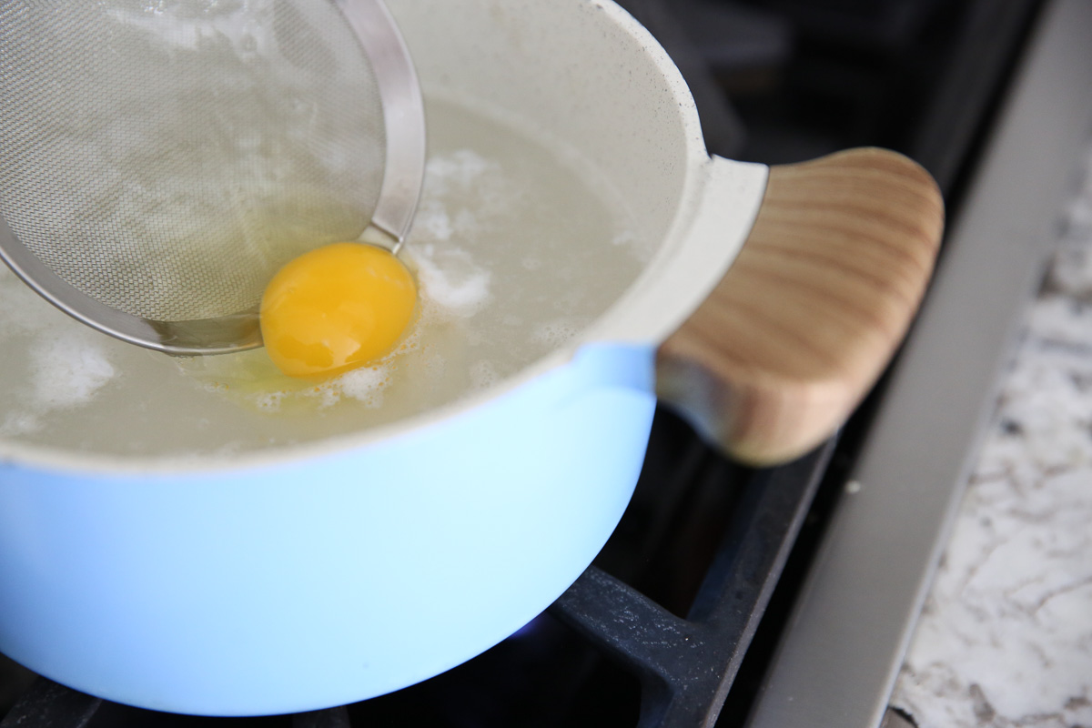 placing a raw egg in a pot of water