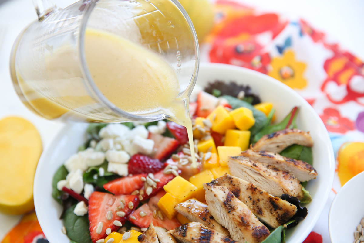 pouring dressing on strawberry mango dressing