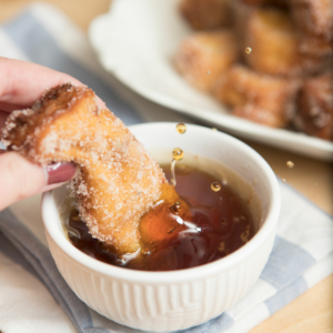 dunking french toast stick in maple syrup