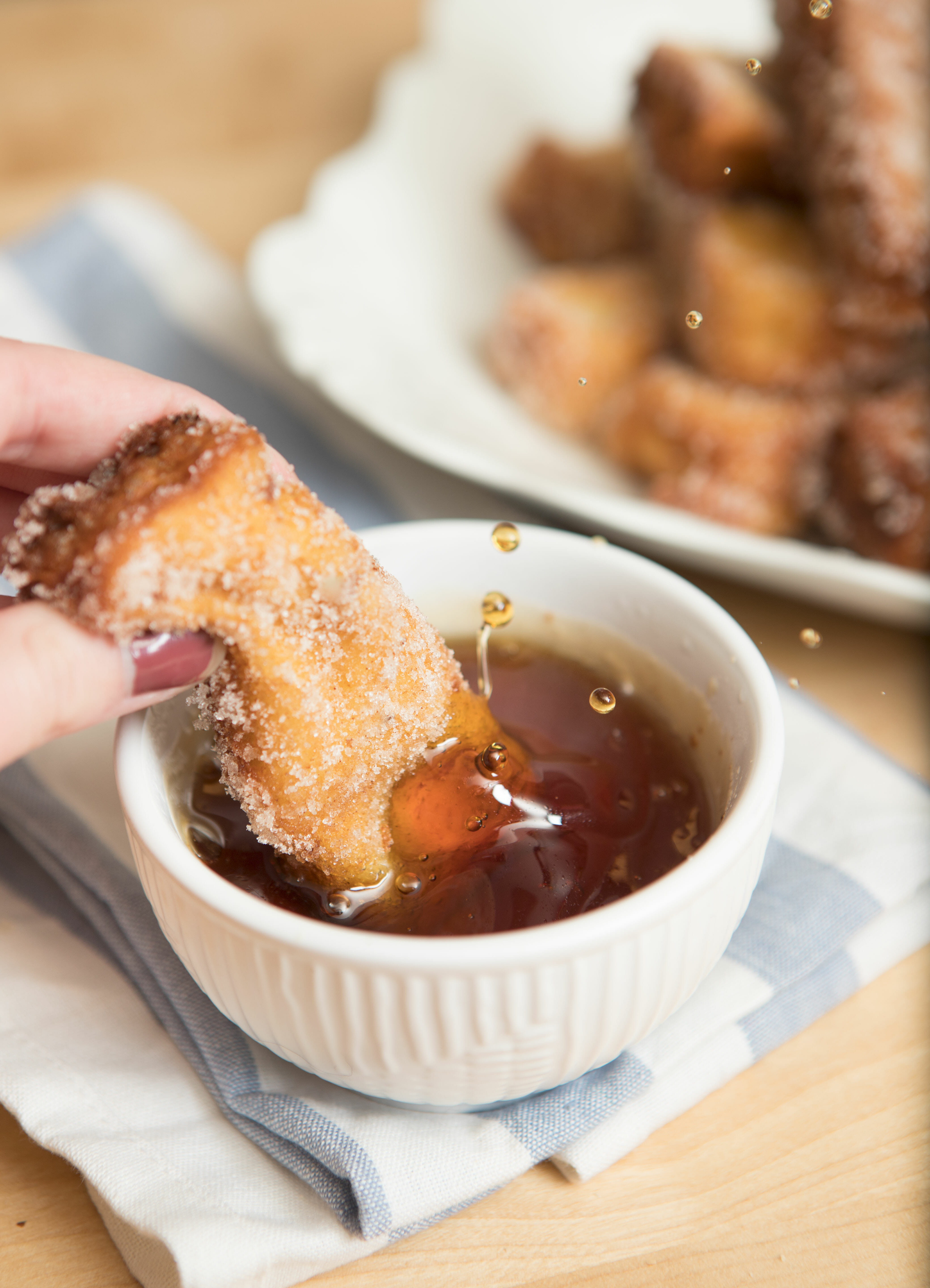 dunking french toast stick in maple syrup