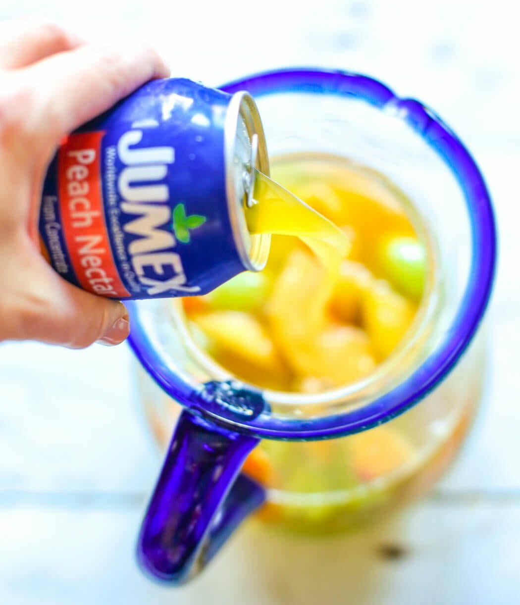 adding orange juice to virgin white peach sangria from Our Best Bites